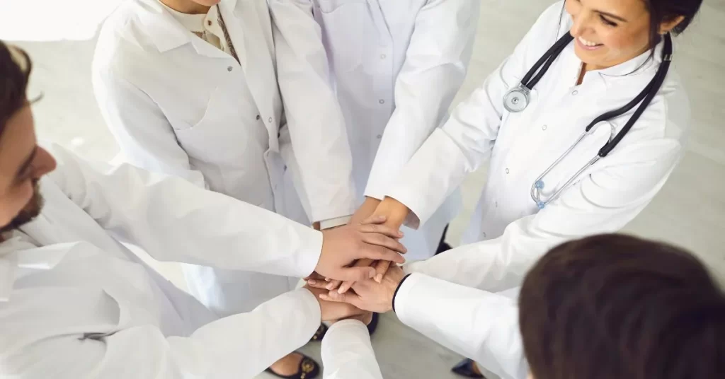 Zespół lekarzy Kliniki TRT łączy ręce w geście jedności, symbolizując współpracę specjalistów w leczeniu pacjentów z niedoborem testosteronu