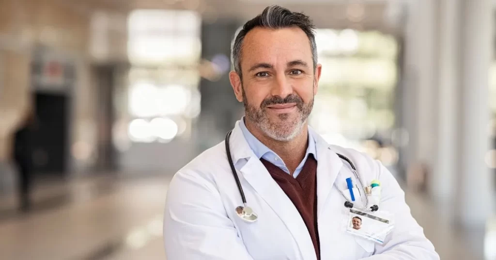 Lekarz z zarostem i męskimi rysami twarzy tłumaczy wpływ testosteronu na wygląd mężczyzn