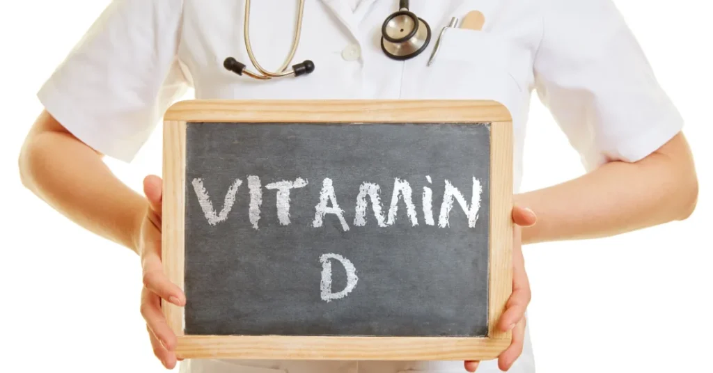 Doktor trzyma tablicę na której widnieje napis "Witamina D"